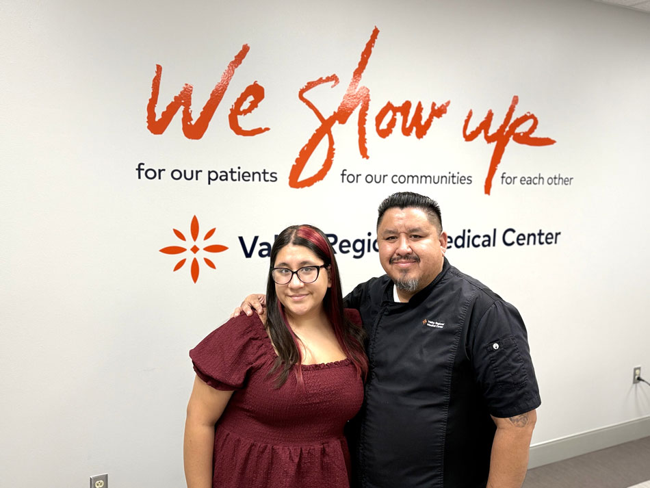 Garza family: Juan and Mariela Garza in front of we show up sign.